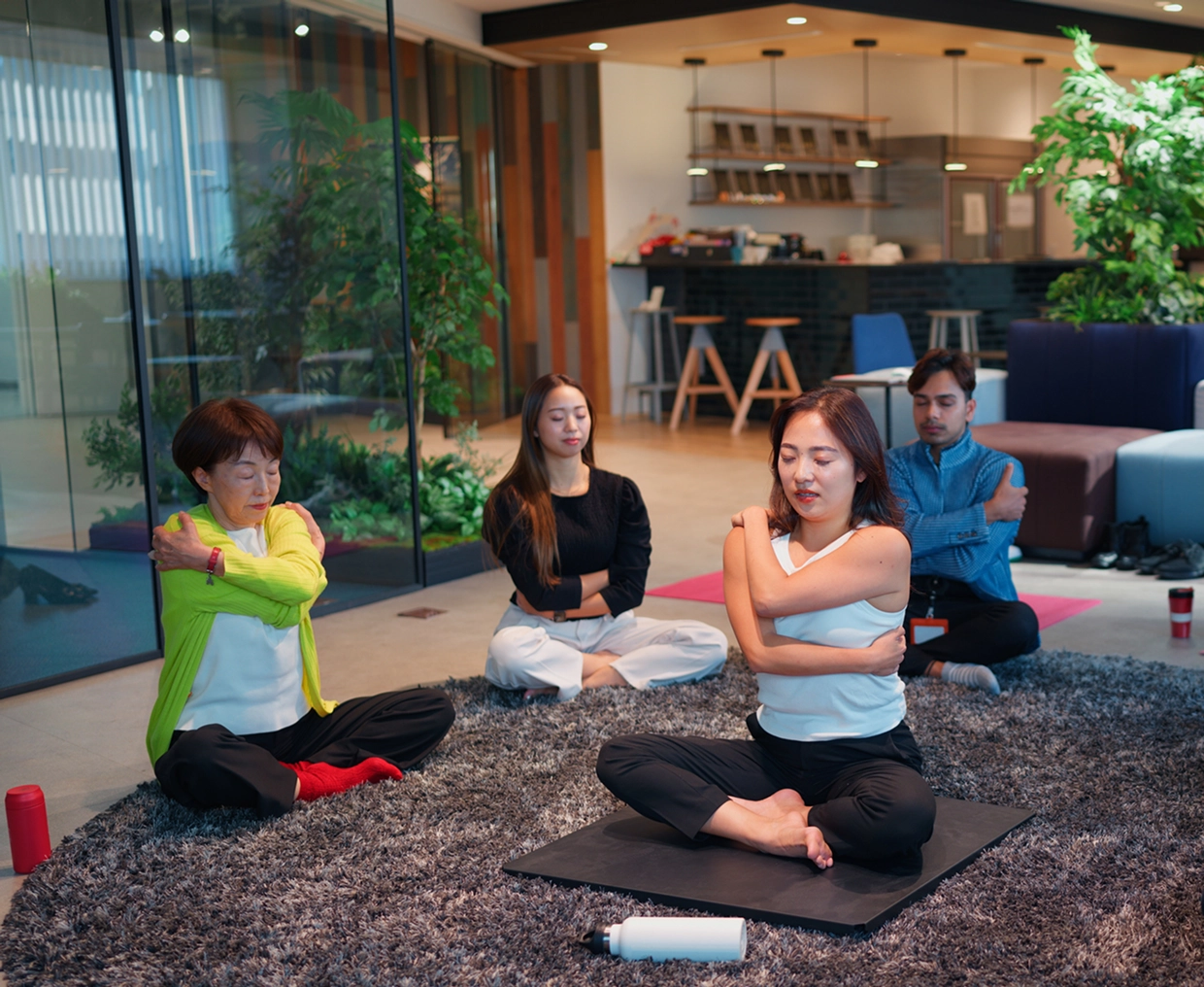 Group meditating on yoga mats indoors.